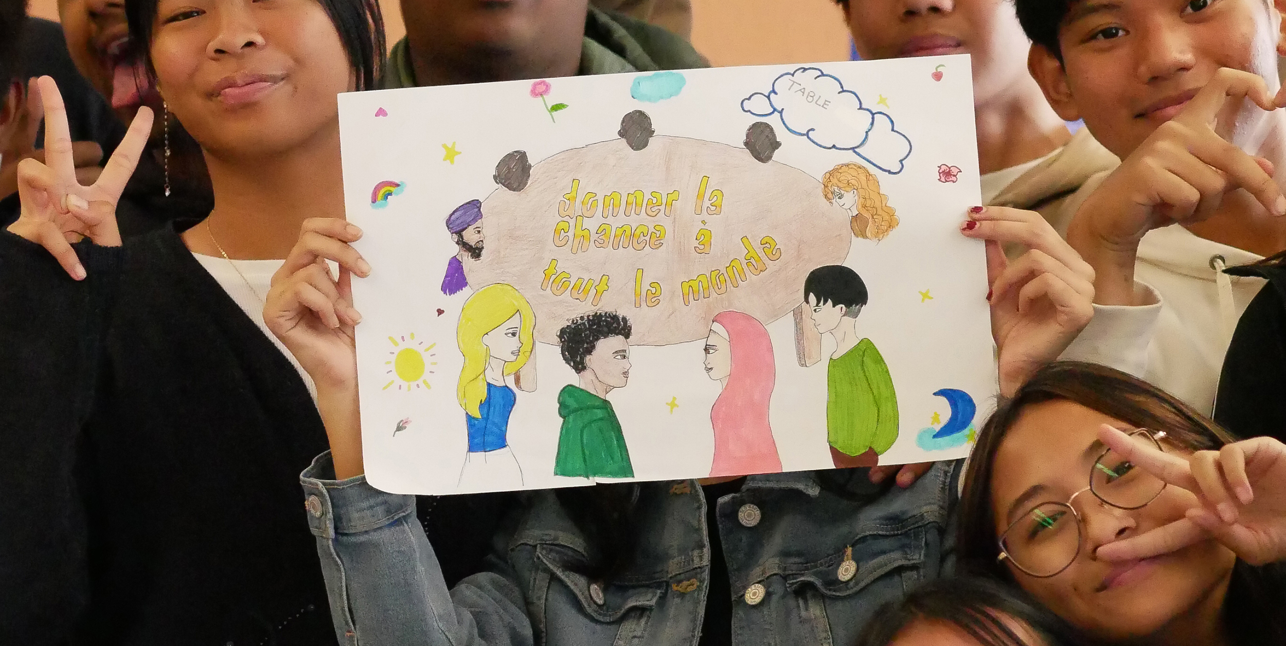des élèves de secondaire 4 tiennent une affiche qui dit " Donner la chance à tout le monde"