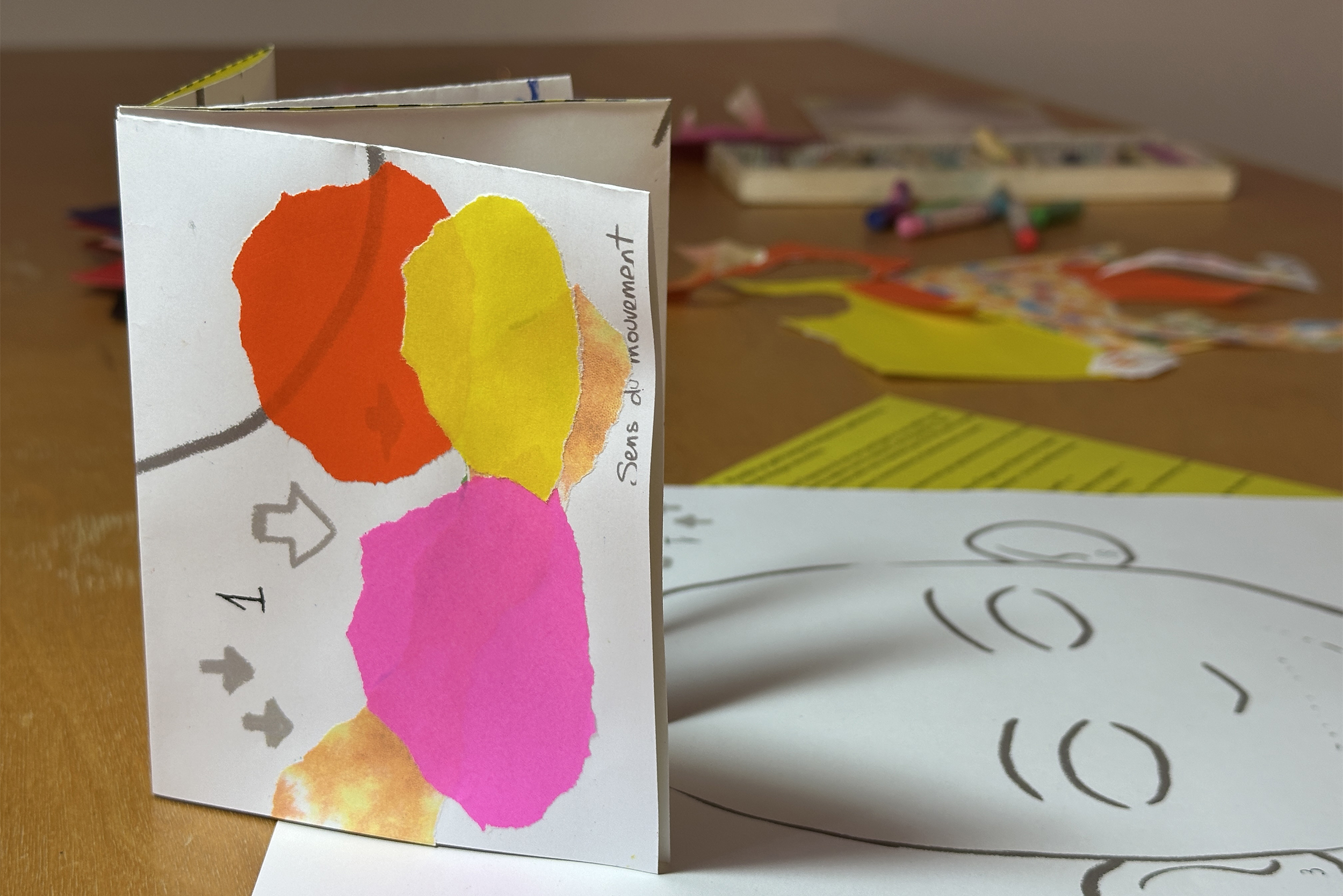 Un carnet de papier des exemples de feuilles à plier pour l'obtenir, et le matériel pour le remplir (pastels et collages).